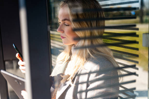 istock Young woman using a mobile phone and a digital tablet outdoors stock photo 1206692900