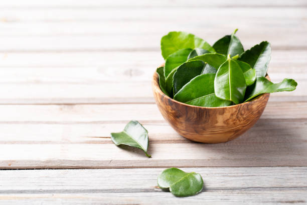 istock Kaffir lime Leaves in a wooden bowl on light table 1206696614