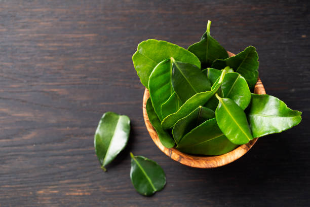 istock Kaffir lime Leaves in a wooden bowl on a dark table. 1206696651
