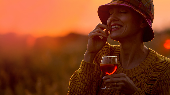 Woman with a cocktail over suset sky in orange colors