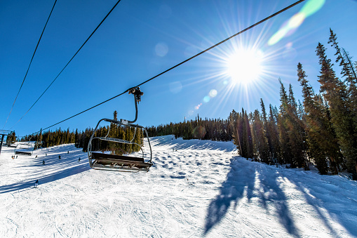 A ski lift up the side of a mountain at Winter Park, Colorado on a clear, mild winter afternoon.