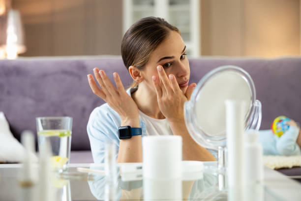 istock Smiling beautiful lady using face cream in room 1206701370