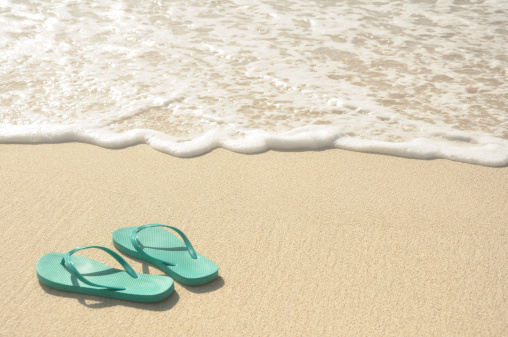 Green Flip Flops on a Sandy Beach