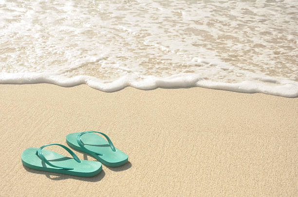 Aqua blue flip flops in the sand near the waves Green Flip Flops on a Sandy Beach thong stock pictures, royalty-free photos & images