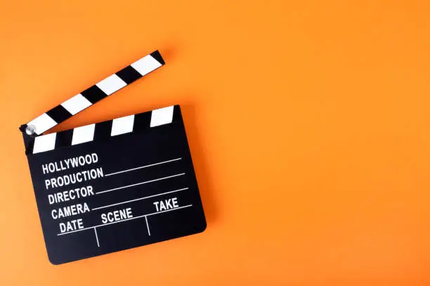 Photo of Movie clapper board on orange background with copy space.