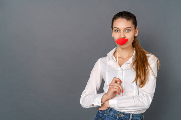istock Young woman student studio isolated on gray posing with crafted red lips 1206705420