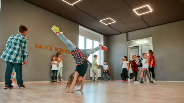 breakdance. porträt eines kleinen mädchens in voller länge, das während eines choreographie-unterrichts im tanzstudio auf ihren händen steht - dancing school stock-fotos und bilder