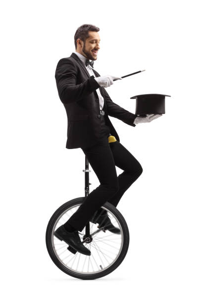 istock Magician performing a magic trick with a wand and a hat and riding a unicycle 1206709407
