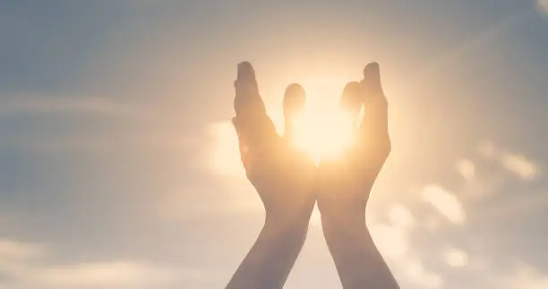 Photo of Persons hand holding sun in palm feeling energized. Spiritual, mind, body concept.