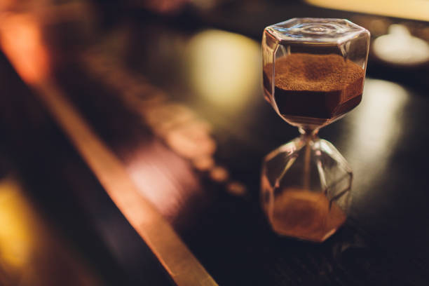 istock Hourglass with falling sand inside a glass bulb, passing time or lost time on a dark background with space for text. 1206719022