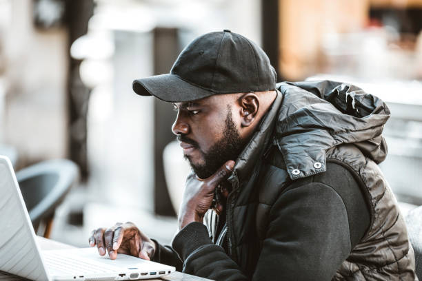 istock Happy black guy sitting at outdoor cafe with laptop computer 1206721073