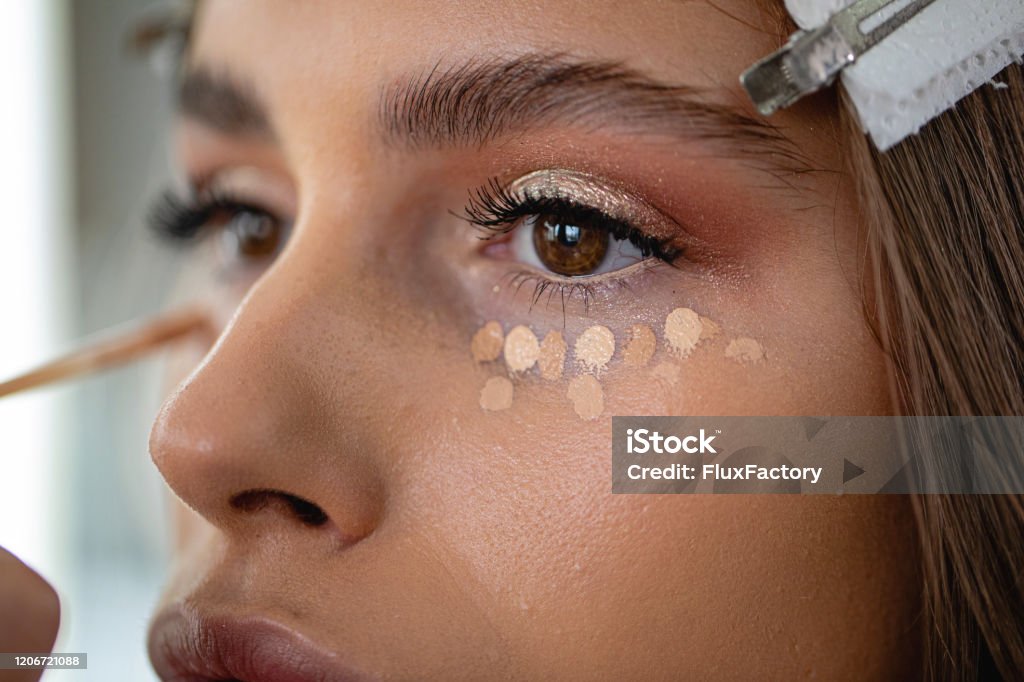 Skin care business Professional model in a beauty salon enjoying getting makeup on Concealer Stock Photo