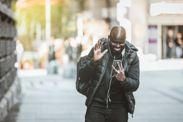 istock Smiling man walking with backpack smart phone and headphones 1206722077