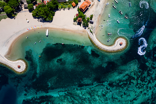 Abstract view taken directly above and in bird eye mode of the coastline of Nusa Dua on the southern part of Bali with a white sand beach facing a crystal clear lagoon