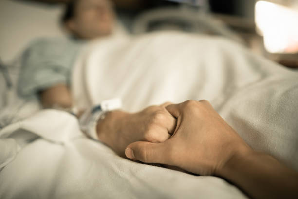 hombre sosteniendo a la mujer de la mano en la cama del hospital. tomar las manos en la cama del hospital - muerte fotografías e imágenes de stock