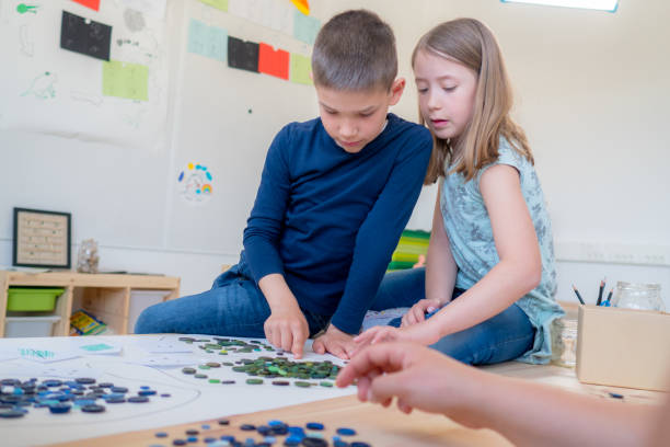 istock Boy and girl playing a game with buttons in class 1206726743