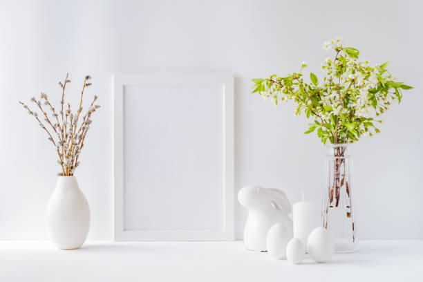 istock Home interior with easter decor. Mockup with a white frame and spring flowers in a vases on a light background 1206728020
