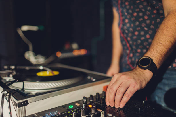 istock Dj hands on equipment deck and mixer with vinyl record at party. 1206728938