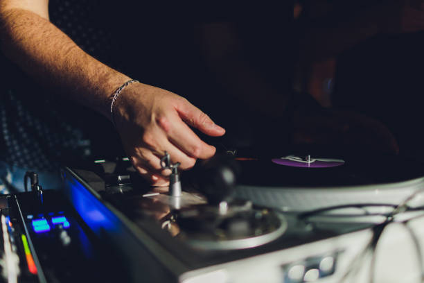 istock Dj hands on equipment deck and mixer with vinyl record at party. 1206728951