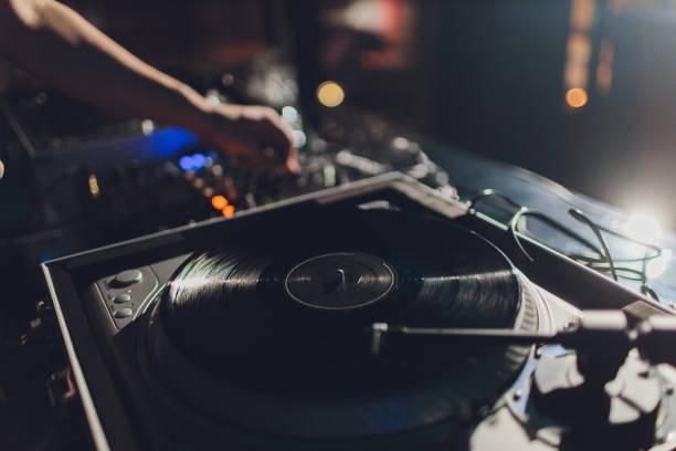 istock Dj hands on equipment deck and mixer with vinyl record at party. 1206729122