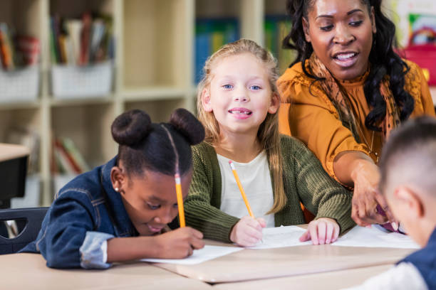 istock Girl with teacher and classmates in elementary school 1206735122