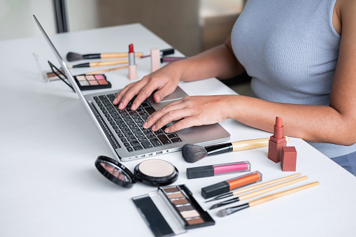 Business online on social media, Beautiful woman is watching online blogger tutorial on laptop, showing present tutorial beauty cosmetic using product makeup.