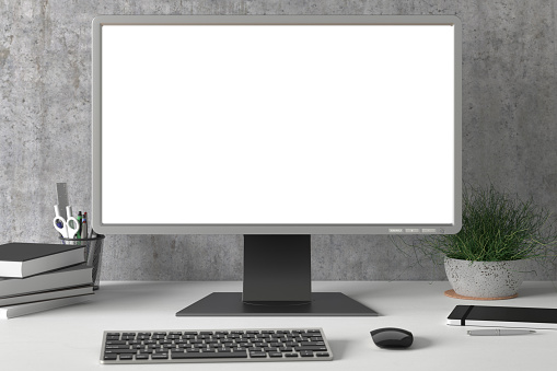 Workspace with blank computer monitor white screen mock up on the white desk near concrete wall.