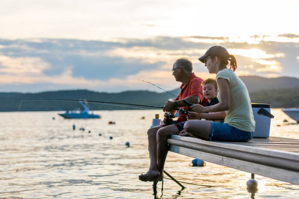 grand-père, mère et petit-fils pêchant au coucher du soleil en été - fishing lake grandfather grandson photos et images de collection