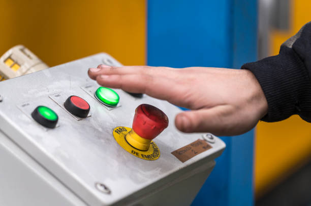 Hand pressing the red emergency button or stop button for industrial machine, Emergency Stop for Safety.