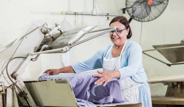 istock Senior woman working at dry cleaners using clothes press 1206738934