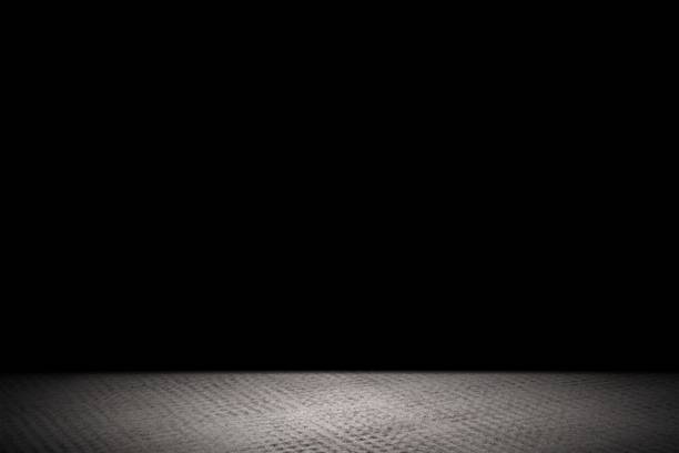 istock Light shining down on rough gray concrete floor in dark room with copy space, abstract background 1206740907