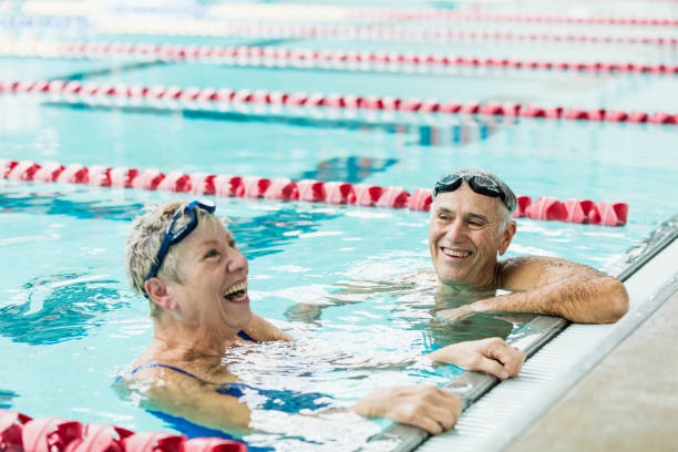 couples aînés s’exerçant ensemble, tours de natation - active seniors retirement enjoyment swimming pool photos et images de collection