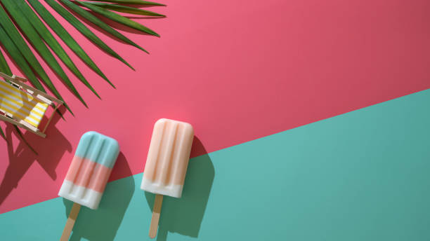 Top view of two colourful popsicles with coconut leaves and decorations of minimal summer concept