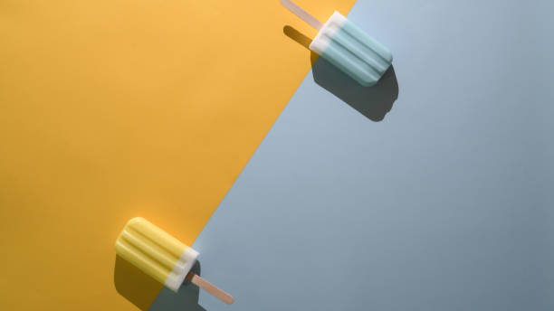 Top view of lime and blue raspberry flavour popsicles and copy space on flat lay yellow and  blue background