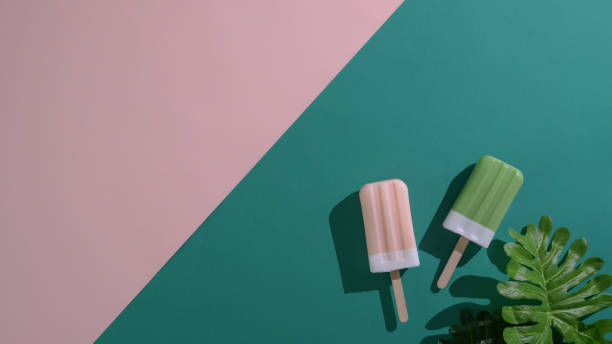 Top view of green tea and strawberry flavour popsicles on flat lay green and pink background
