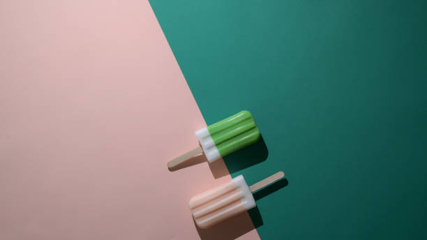 Overhead shot of green tea and strawberry flavour popsicles and copy space on flat lay green and pink background