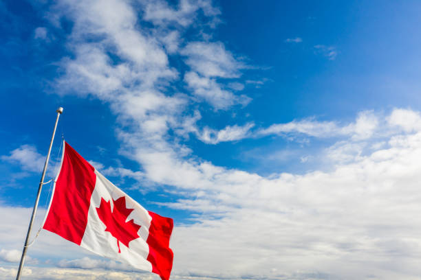 istock Canadian Flag flailing in the wind. Blue sky with clouds in background 1206750875