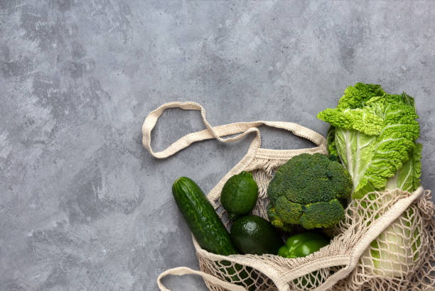 istock Green fresh vegetables in a string bag on a gray background 1206751905