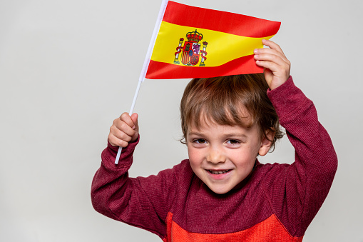 Caucasian blond Smiling Spanish Child boy looking at the camera waving the flag of Spain
