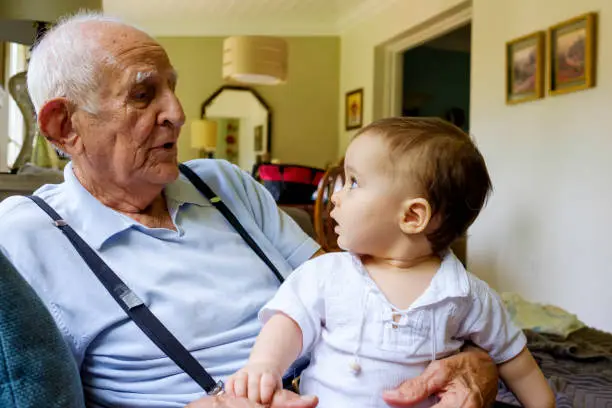 Cute baby boy with great grandfather in a home setting.