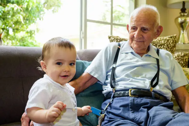 Cute baby boy with great grandfather in a home setting.