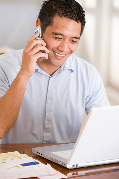 istock Man at home on mobile phone using laptop smiling 120676515