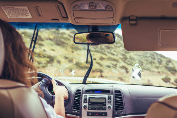 istock Woman driving. car wipers clean windshield. Back view 1206768515