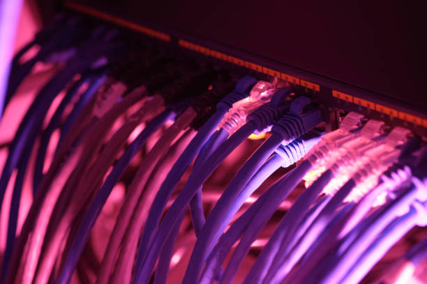 istock Close up UTP CAT6 cable with red lighting and high speed network router switch in a technology data center room. 1206770888