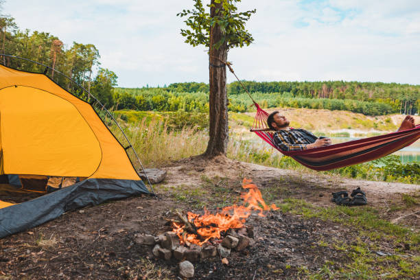 istock man laying on hammock at lake beach near camp fire 1206773201