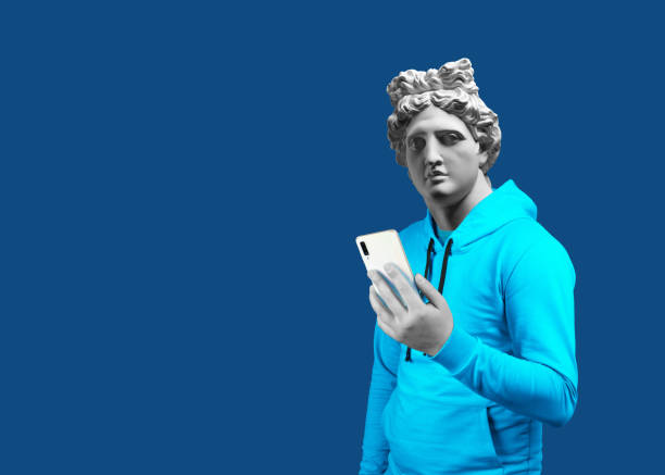 Modern art collage. Concept portrait of a man  holding mobile smartphone using app texting sms message. Gypsum head of of Apollo. Man in suit. On a blue background.