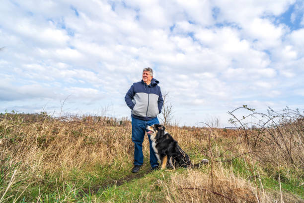 istock Man walking on grassland with border collie 1206775940