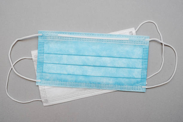 istock Surgical mask with rubber earband. A typical three-layer surgical mask covering the nose and mouth. 1206775953