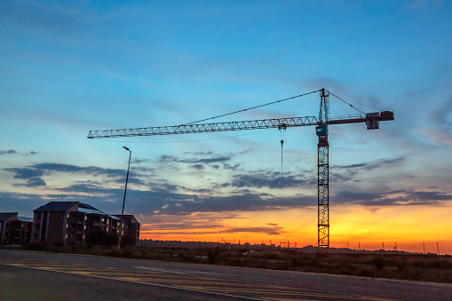 Sunset silhouette construction crane at a retirement building site, at Northgate, South Africa
