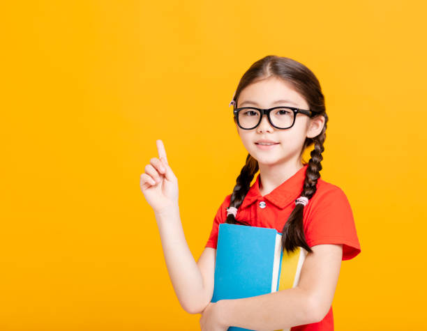 Adorable student girl  holding the books  and showing something Adorable student girl  holding the books  and showing something elementary student pointing stock pictures, royalty-free photos & images